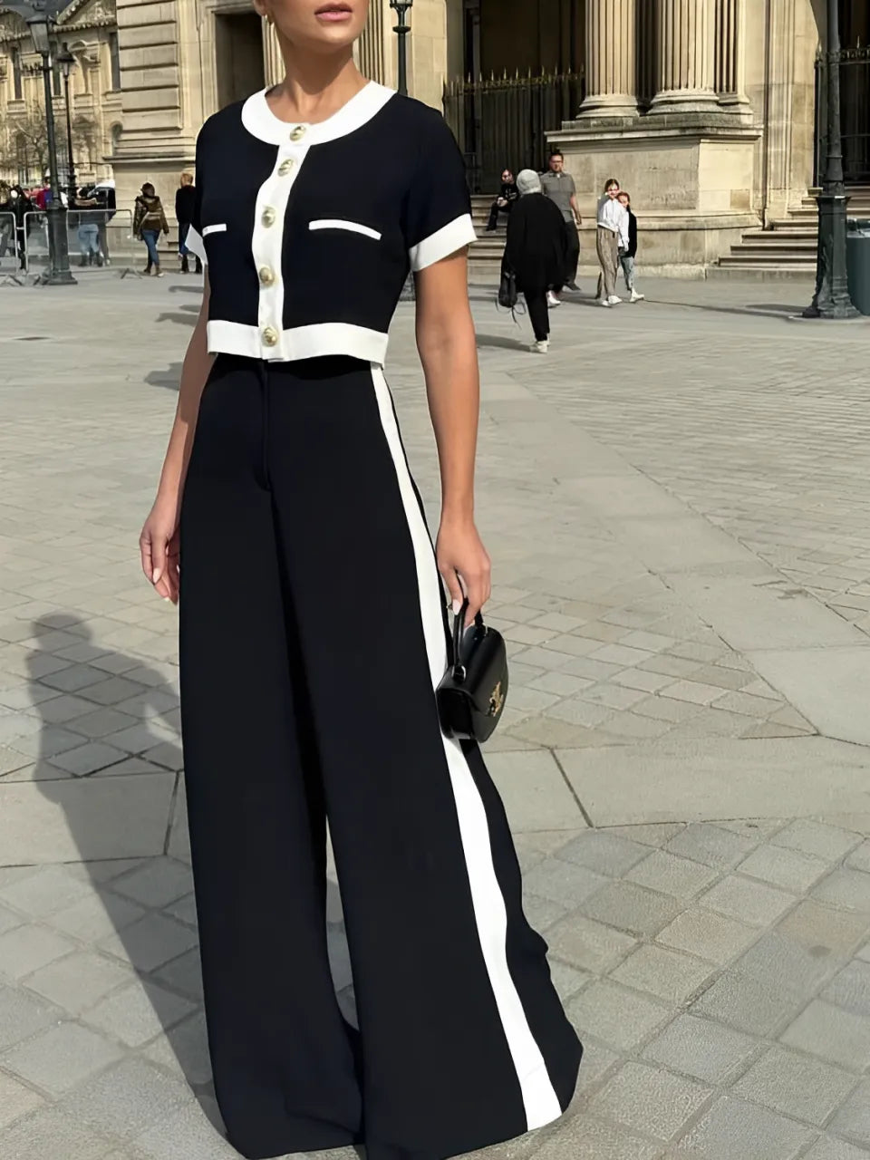 Conjunto Victoria preto com detalhes em branco, composto por blusa cropped de botões dourados e calça pantalona de cintura alta estilo alfaiataria clássica