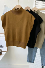 Modelo vestindo regata de tricô gola alta na cor camel, com ombros estruturados estilo muscle tee e modelagem soltinha na cintura