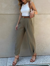 Modelo vestindo Calça Ester de alfaiataria slim na cor verde militar, com cintura média, pregas frontais elegantes e cinto fino ajustável na cintura