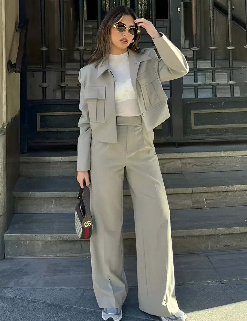 Mulher vestindo Conjunto Emily de alfaiataria premium, combinando jaqueta estilo bomber moderna e calça pantalona de cintura alta que alonga a silhueta."