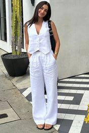 Modelo vestindo Conjunto Glover bege claro, composto por colete de alfaiataria com botões frontais e calça pantalona ampla de cintura alta