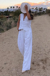 Modelo vestindo Conjunto Glover bege claro, composto por colete de alfaiataria com botões frontais e calça pantalona ampla de cintura alta