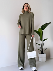 Modelo vestindo Conjunto Grace na cor Verde Militar, composto por suéter de tricô canelado com gola alta e corte mullet, combinado com calça pantalona ampla e fluida."