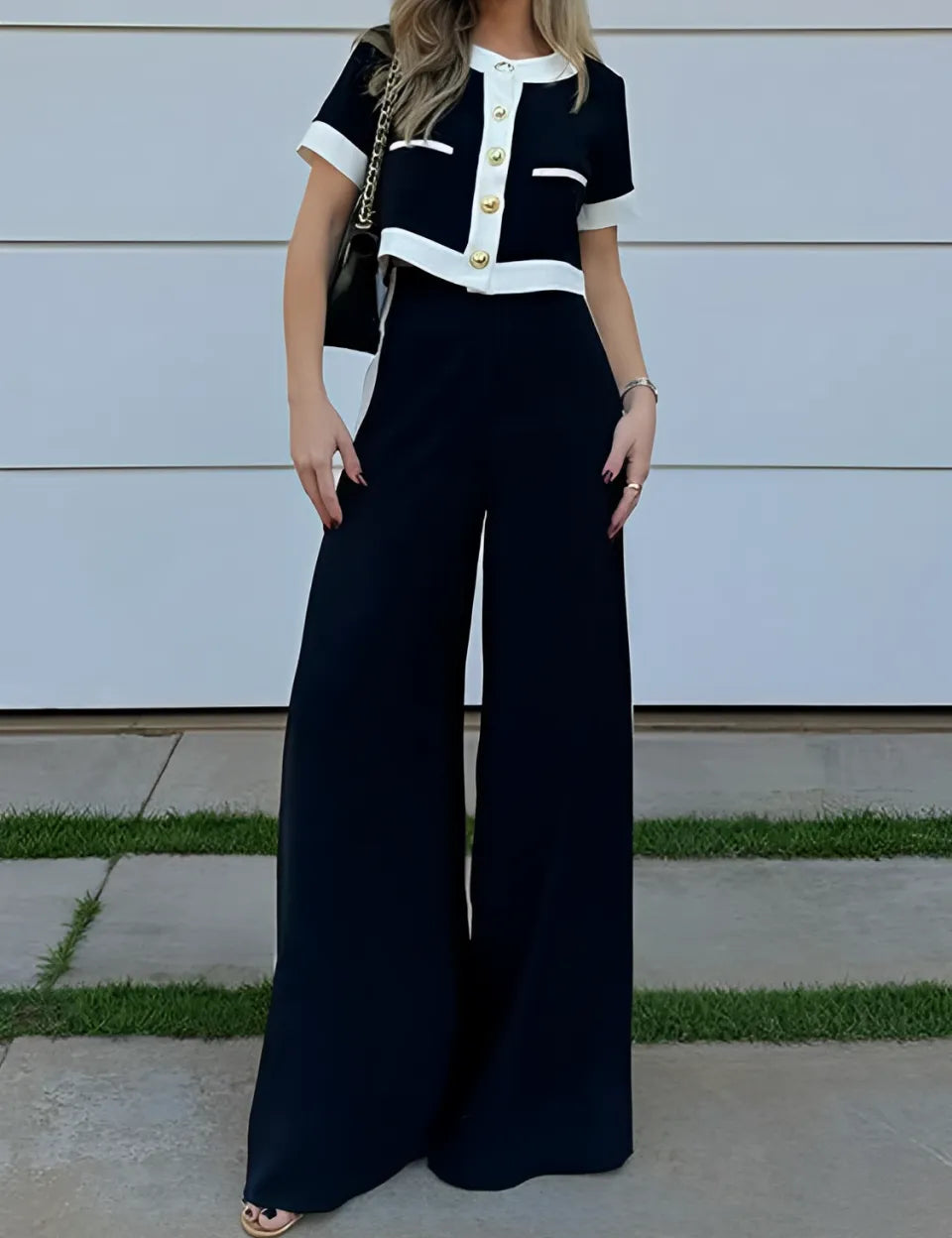 Conjunto Victoria preto com detalhes em branco, composto por blusa cropped de botões dourados e calça pantalona de cintura alta estilo alfaiataria clássica