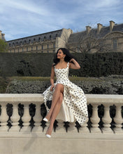 Modelo usando Vestido Solana branco com bolas pretas (poá), modelagem acinturada com decote quadrado, alças médias e saia ampla rodada