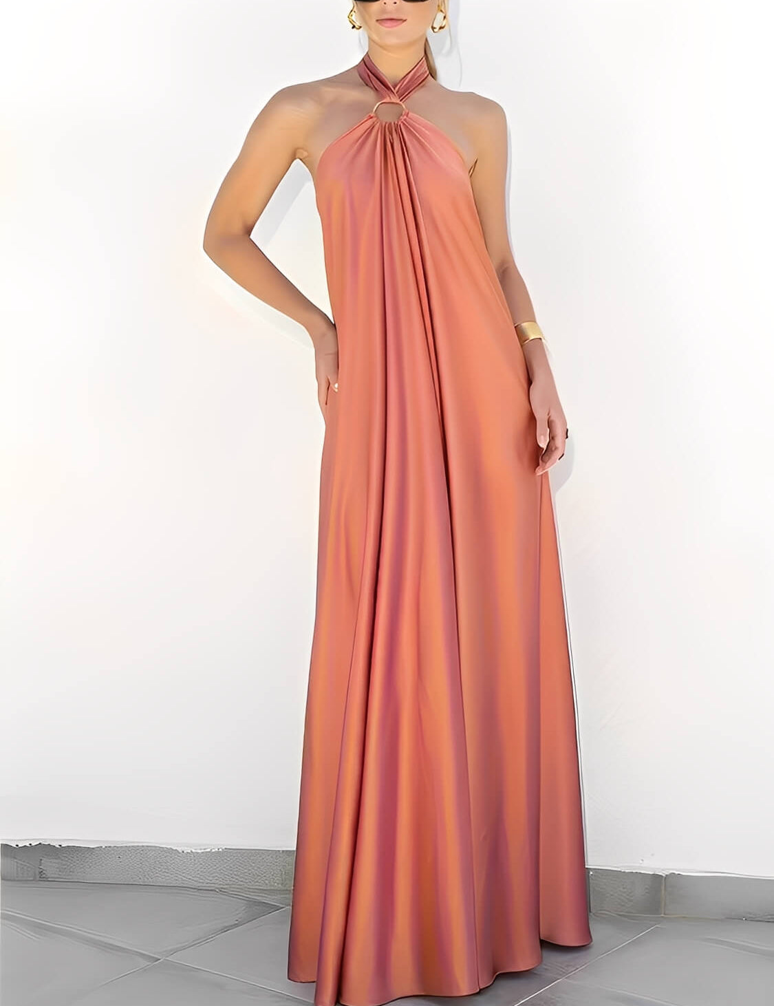 Modelo usando vestido longo Hailey acetinado salmão com gola halter, argola dourada no pescoço e costas nuas, estilo festa elegante