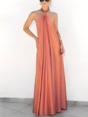 Modelo usando vestido longo Hailey acetinado salmão com gola halter, argola dourada no pescoço e costas nuas, estilo festa elegante