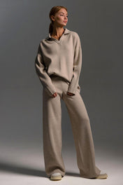 Modelo vestindo Conjunto Clarice de tricô off-white, composto por blusão oversized de mangas longas com gola polo aberta e calça pantalona solta