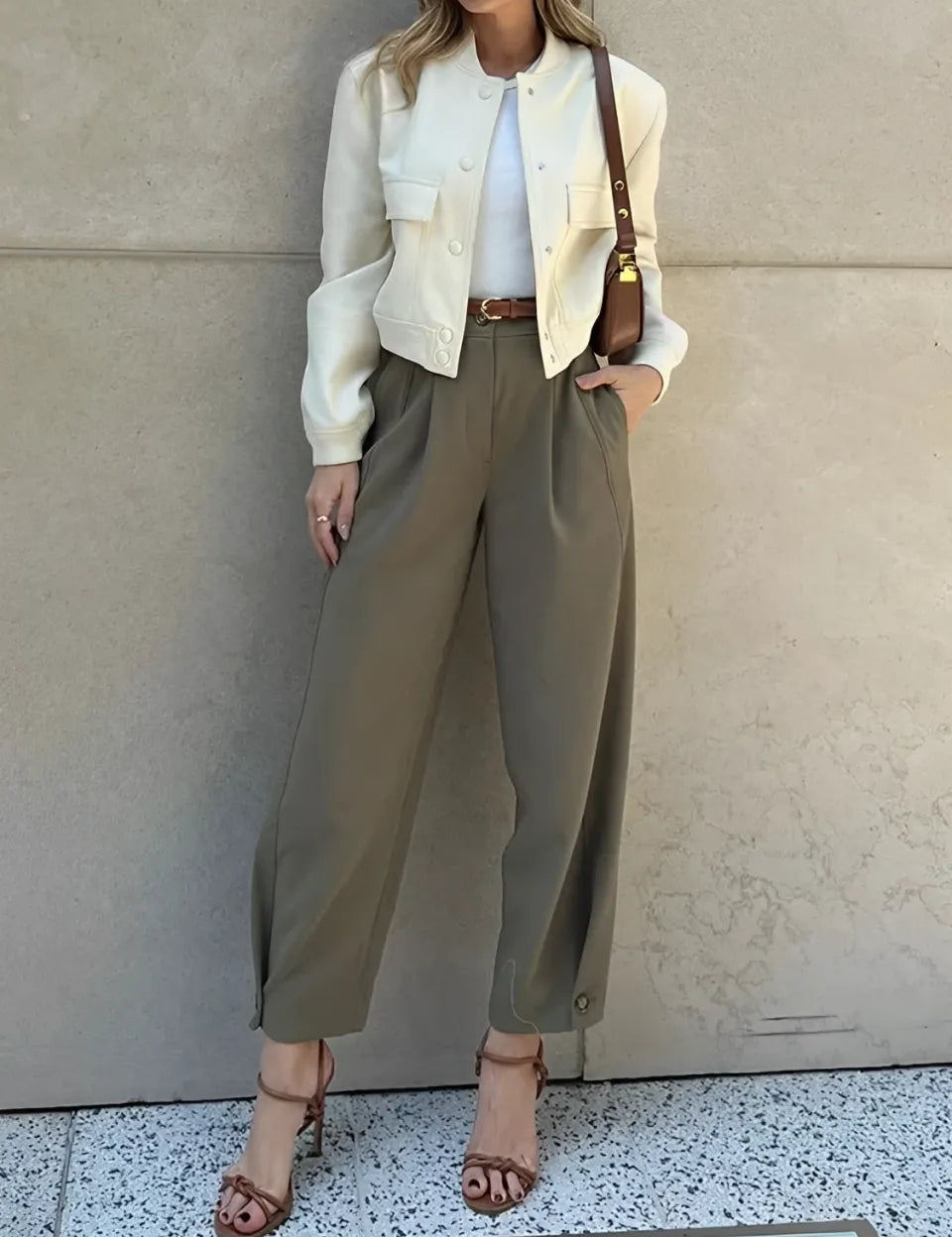 Modelo vestindo Calça Ester de alfaiataria slim na cor verde militar, com cintura média, pregas frontais elegantes e cinto fino ajustável na cintura