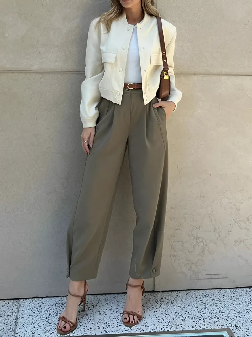 Modelo vestindo Calça Ester de alfaiataria slim na cor verde militar, com cintura média, pregas frontais elegantes e cinto fino ajustável na cintura