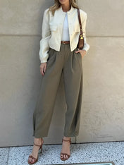 Modelo vestindo Calça Ester de alfaiataria slim na cor verde militar, com cintura média, pregas frontais elegantes e cinto fino ajustável na cintura