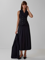 Modelo vestindo conjunto Lizandra all black de alfaiataria, com colete de botões duplos e saia midi plissada de caimento estruturado
