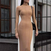 Modelo vestindo Vestido Amira marrom café, comprimento midi alongado, tecido canelado ajustado ao corpo, gola alta e mangas longas, estilo minimalista elegante.
