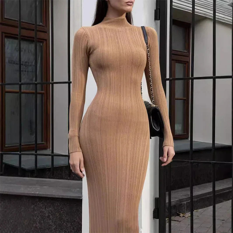 Modelo vestindo Vestido Amira marrom café, comprimento midi alongado, tecido canelado ajustado ao corpo, gola alta e mangas longas, estilo minimalista elegante.