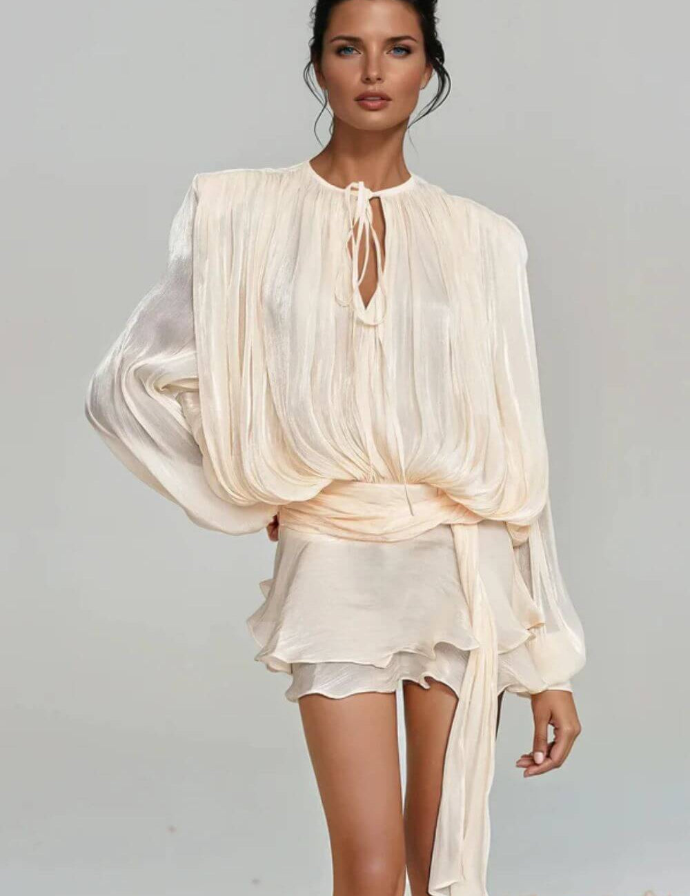 "Modelo vestindo Vestido Giulieta curto em tecido acetinado com textura amassadinha (crushed), mangas longas bufantes volumosas e saia de babados em camadas.