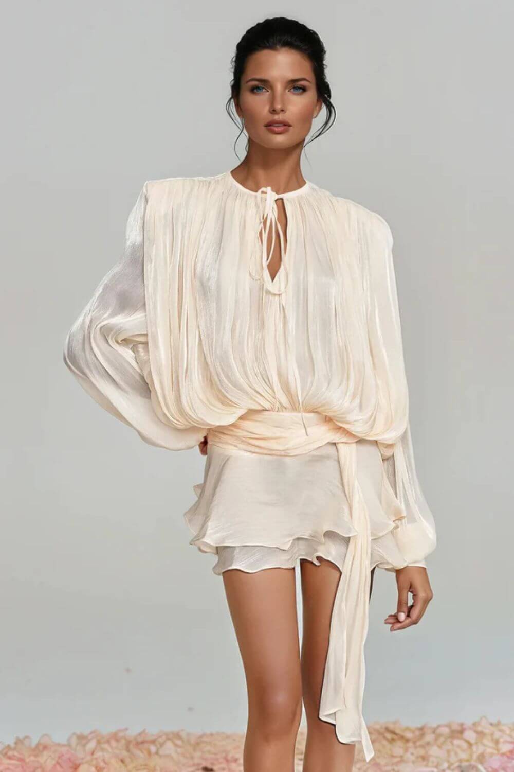 "Modelo vestindo Vestido Giulieta curto em tecido acetinado com textura amassadinha (crushed), mangas longas bufantes volumosas e saia de babados em camadas.