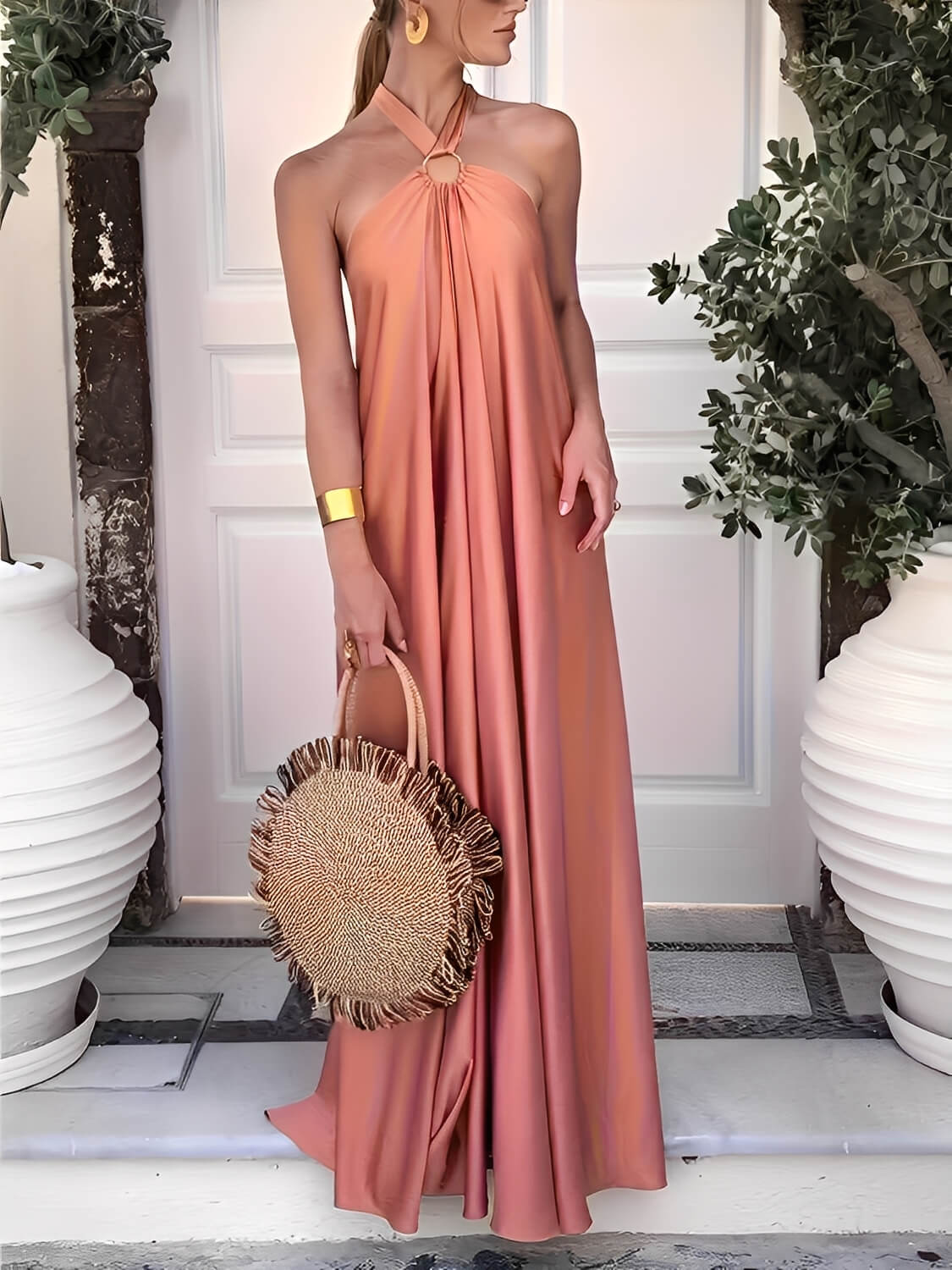 Modelo usando vestido longo Hailey acetinado salmão com gola halter, argola dourada no pescoço e costas nuas, estilo festa elegante