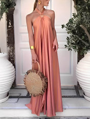 Modelo usando vestido longo Hailey acetinado salmão com gola halter, argola dourada no pescoço e costas nuas, estilo festa elegante