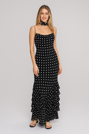 Modelo loira em evento noturno usando Vestido Sofi longo preto com bolinhas brancas (poá), alças finas, babados na barra e lenço no pescoço combinando